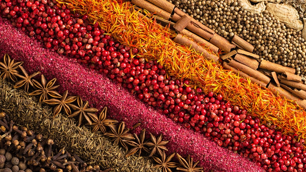 Rows of spices, such as allspice, clove, cumin, star anise, red peppercorns, saffron, cinnamon, coriander